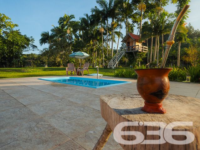 Apresentamos uma oportunidade excepcional para quem busca tranquilidade e conforto em um ambiente naturalmente deslumbrante. Este sítio localizado em São João do Itaperiú, SC, oferece uma área total de 100.000 m² de terreno plano, envolto em uma paisagem exuberante e benfeitorias que elevam a qualidade de vida no campo.

A chácara é composta por três residências, garantindo flexibilidade para hospedagem de familiares ou como potencial fonte de renda com locação. A casa principal é uma joia arquitetônica, com três pavimentos no estilo colonial, incluindo uma suíte master e mais uma suíte, ambos ricamente detalhados com madeira nobre de itaúba em portas, janelas e sacadas. Aquecimento solar e água de poço artesiano asseguram conforto e sustentabilidade.

As áreas de convivência são amplas e acolhedoras, com duas salas espaçosas, cozinha prática e lavabo, tudo sob a cobertura majestosa que confere charme e elegância ao ambiente. A propriedade também inclui uma segunda casa com dois quartos e uma cozinha conjugada com a sala, e uma terceira casa em fase de finalização, prometendo ainda mais espaço e comodidade.

Para os amantes do lazer ao ar livre, a chácara oferece uma piscina imersa na natureza, áreas de festa com churrasqueira e fogão a lenha, perfeitas para receber amigos e familiares. O terreno é adornado por um belo jardim, um pomar diversificado com várias frutíferas e até um ribeirão com nascente própria, além de dois tanques de peixes, ideal para os entusiastas da pesca.

Esta propriedade não é apenas uma casa, é um estilo de vida. Imersa em uma área com preservação legal, ela oferece privacidade, conforto e a infinita possibilidade de criar momentos inesquecíveis. Entre o canto dos pássaros e o murmurar das águas, o sítio é um convite para viver seus dias com mais plenitude e paz.

Venha conhecer seu novo lar no campo, onde cada amanhecer traz a promessa de um novo começo. Aguardamos seu contato para agendar uma visita e experimentar em primeira mão a beleza e tranquilidade que só a 636 Negócios Imobiliários pode oferecer.
 
636 NEGÓCIOS IMOBILIÁRIOS: A SUA MELHOR ESCOLHA
Com mais de 30 anos de experiência, a 636 Negócios Imobiliários é sua parceira ideal para encontrar o imóvel perfeito. Estamos prontos para ajudá-lo a fazer deste imóvel o seu novo lar.
 
Telefone: (47) 3451-0636
WhatsApp: (47) 99190-0636
 
Não perca esta oportunidade única. Visite nosso site para mais informações: i636.com.br